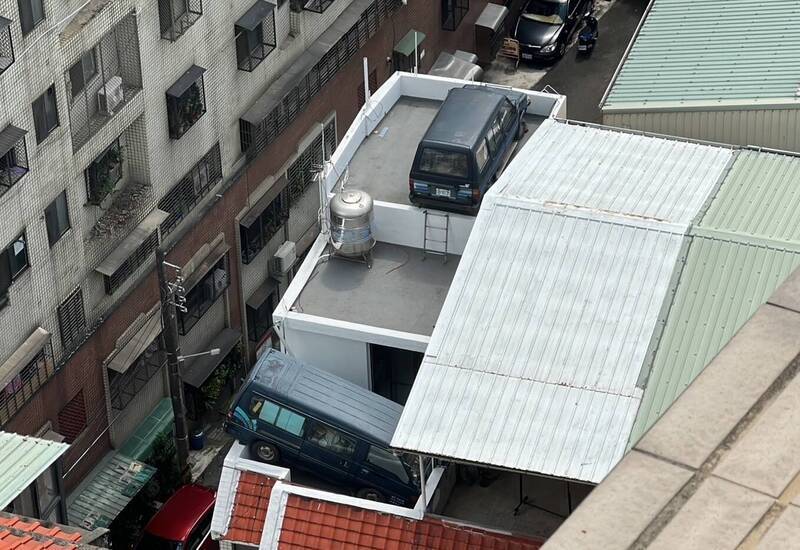 台中市北區東光二街一處透天民宅，2輛廂型車吊放在民宅頂樓，其中1輛廂型車更卡在女兒牆上，從路旁查看還能看見車尾。